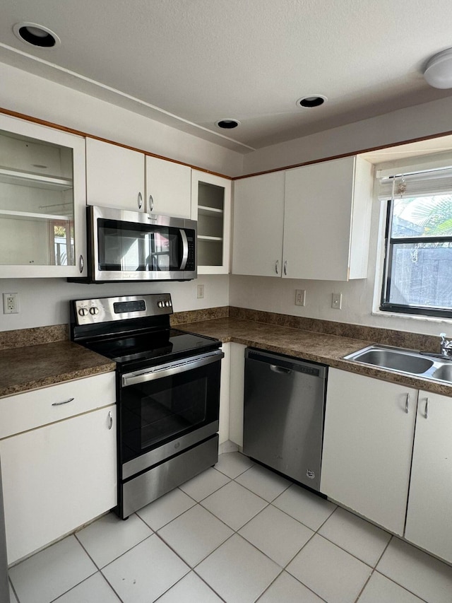 kitchen featuring white cabinetry, sink, light tile patterned flooring, and appliances with stainless steel finishes