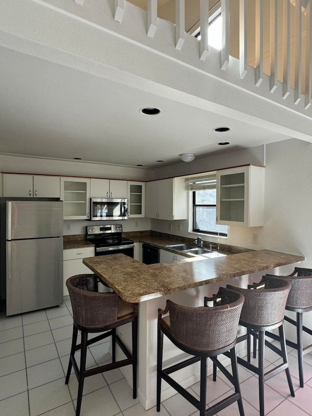 kitchen featuring a kitchen bar, light tile patterned floors, kitchen peninsula, and appliances with stainless steel finishes