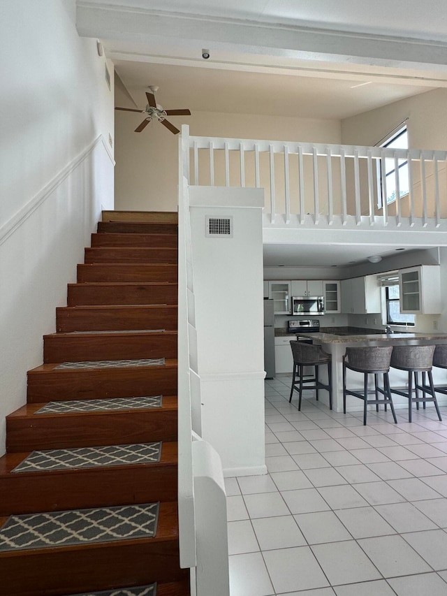 stairs with tile patterned floors, plenty of natural light, and ceiling fan