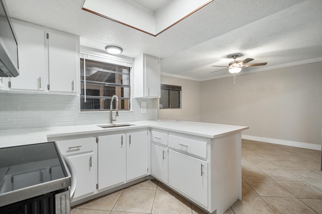 kitchen with range, sink, kitchen peninsula, tasteful backsplash, and white cabinetry