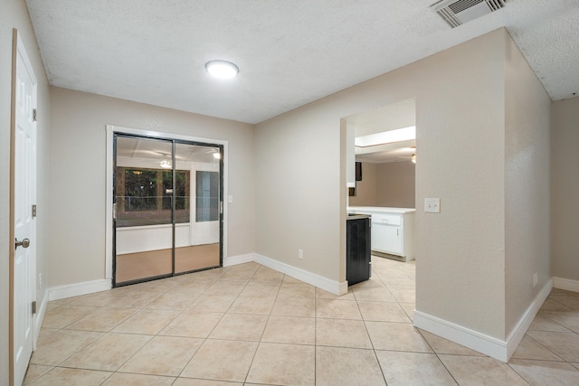 spare room featuring light tile patterned floors and a textured ceiling