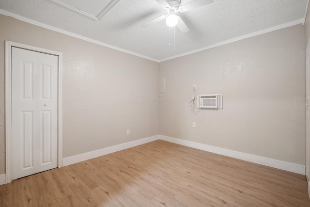 unfurnished room with ceiling fan, light hardwood / wood-style floors, a textured ceiling, and a wall mounted AC