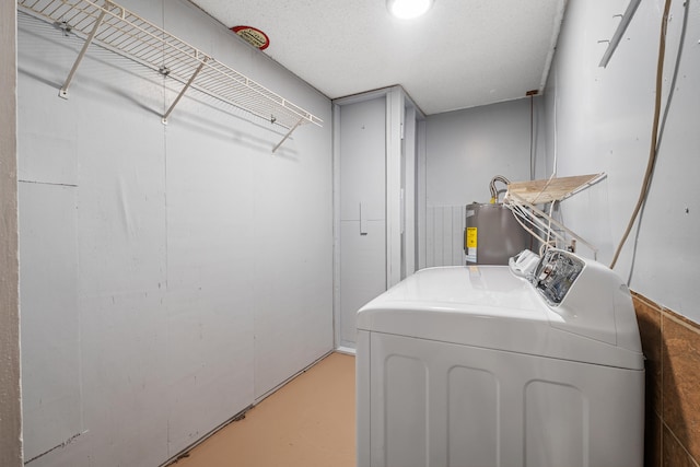 laundry room with washer and dryer, a textured ceiling, and water heater