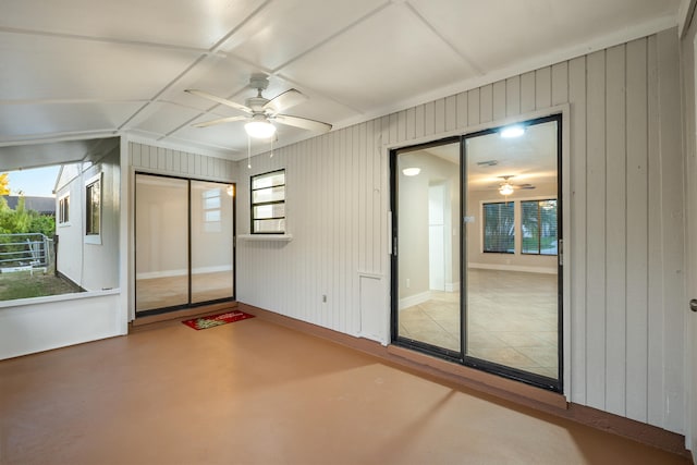 interior space featuring concrete floors, plenty of natural light, wood walls, and ceiling fan