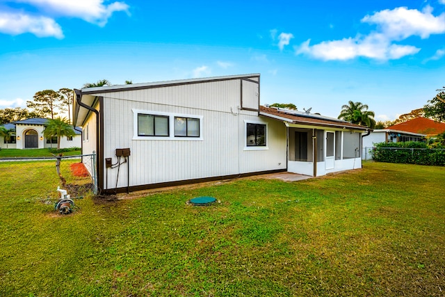 back of property featuring a lawn and a sunroom