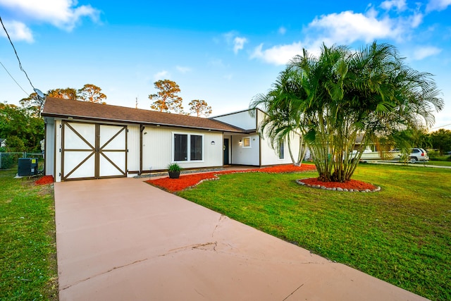 view of front of home with central AC unit, a garage, and a front lawn