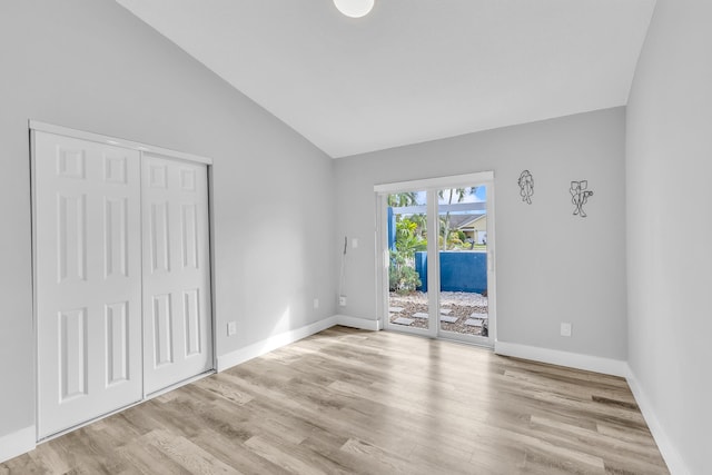 empty room with light hardwood / wood-style floors and vaulted ceiling