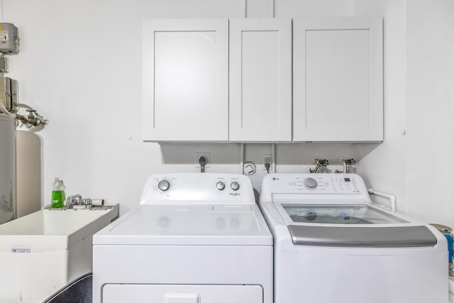 clothes washing area with separate washer and dryer, sink, and cabinets