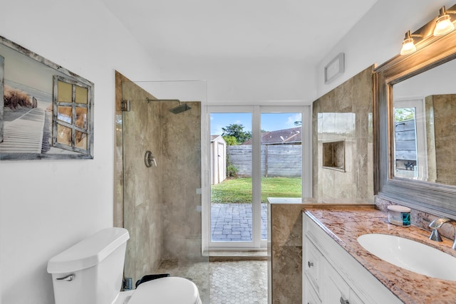 bathroom featuring a tile shower, plenty of natural light, vanity, and toilet