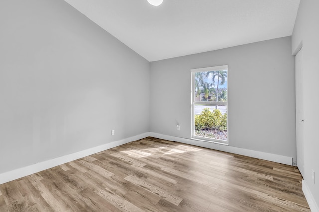 spare room featuring light hardwood / wood-style flooring and vaulted ceiling