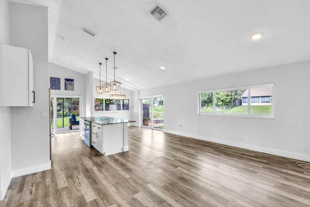 kitchen with a wealth of natural light, white cabinetry, a kitchen island, and vaulted ceiling