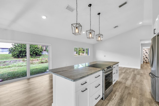 kitchen with lofted ceiling, dark stone countertops, a kitchen island, white cabinetry, and stainless steel appliances