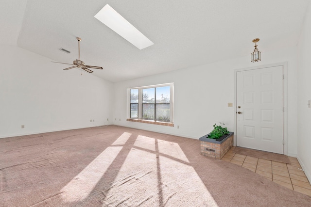 foyer entrance with ceiling fan, vaulted ceiling with skylight, and light tile patterned floors