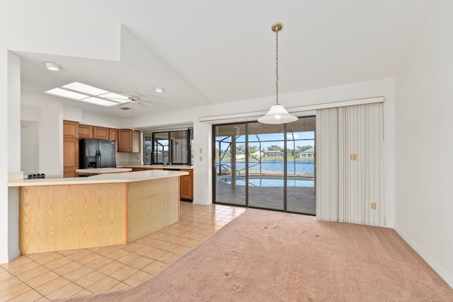 kitchen with ceiling fan, light tile patterned floors, black refrigerator with ice dispenser, kitchen peninsula, and a water view