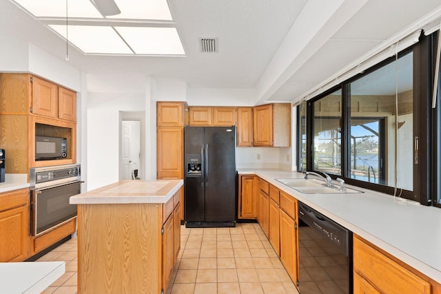 kitchen with light tile patterned flooring, sink, a kitchen island, and black appliances