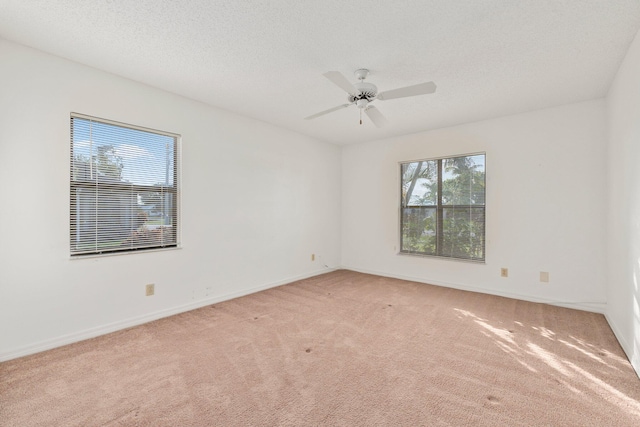 spare room featuring a textured ceiling, ceiling fan, and light carpet