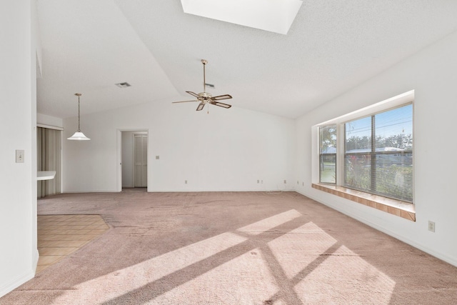 carpeted empty room with ceiling fan and vaulted ceiling with skylight