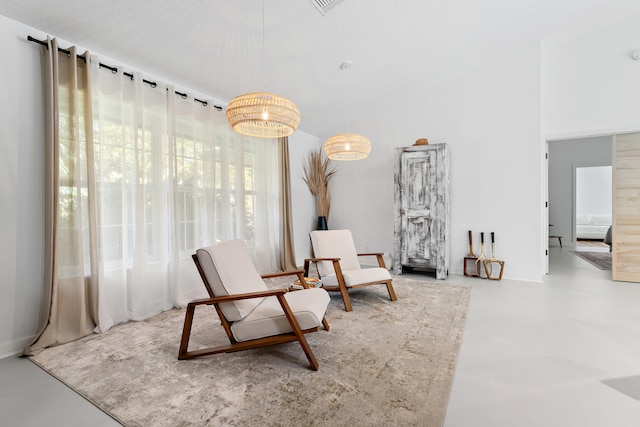 sitting room featuring concrete floors and a notable chandelier