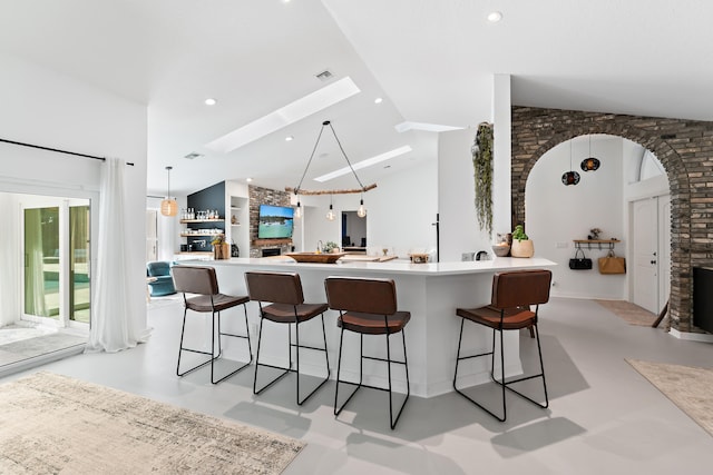 kitchen with a large island, a skylight, high vaulted ceiling, and a breakfast bar area