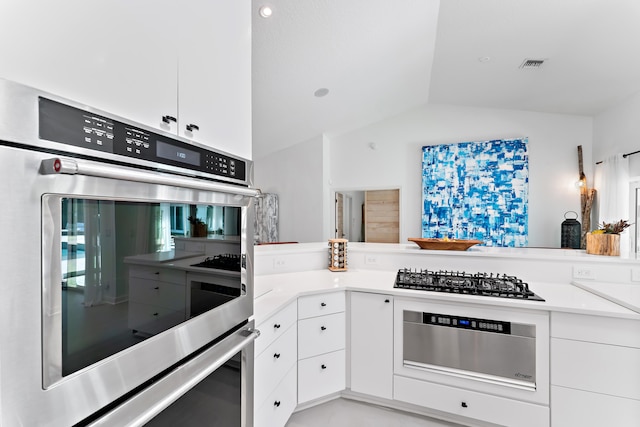 kitchen featuring lofted ceiling, double oven, white cabinetry, and gas stovetop