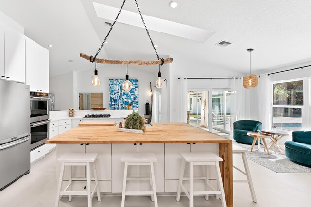 bar featuring butcher block counters, sink, white cabinetry, a textured ceiling, and a fireplace