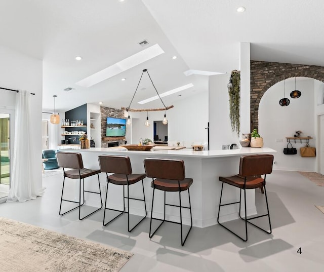 kitchen featuring a fireplace, vaulted ceiling, and a kitchen bar