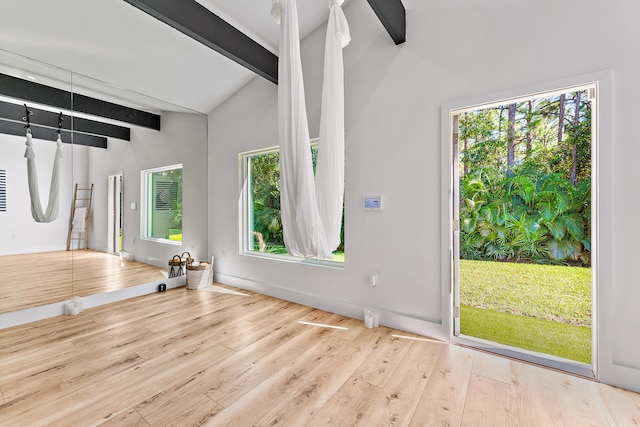 interior space with plenty of natural light, lofted ceiling with beams, and light wood-type flooring