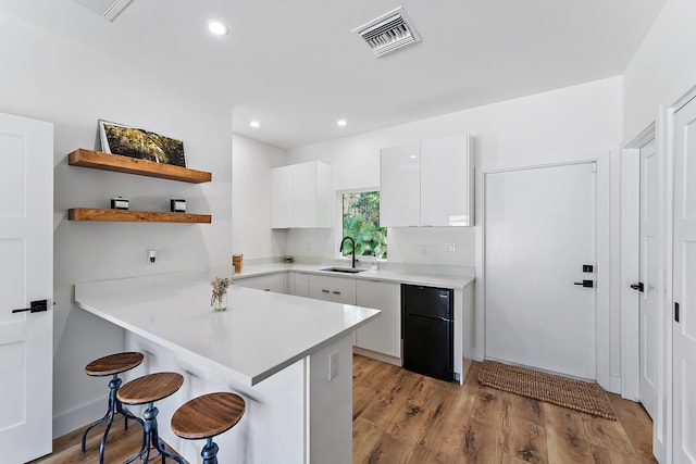 kitchen with white cabinets, black refrigerator, a breakfast bar area, and kitchen peninsula