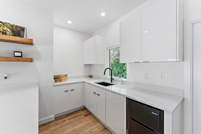 kitchen featuring sink, white cabinetry, and light wood-type flooring