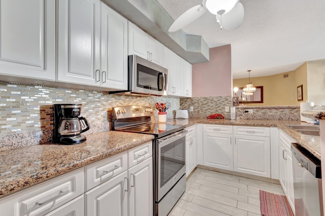 kitchen featuring decorative light fixtures, backsplash, stainless steel appliances, and white cabinetry