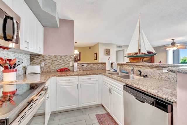 kitchen with white cabinets, sink, appliances with stainless steel finishes, tasteful backsplash, and kitchen peninsula