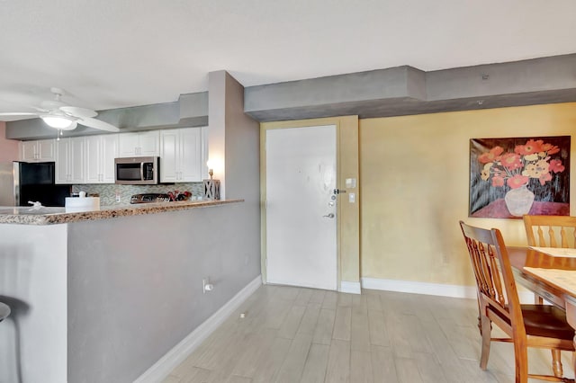 kitchen featuring white cabinetry, ceiling fan, black fridge, backsplash, and light hardwood / wood-style floors