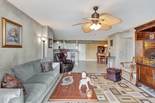 living room with ceiling fan and a textured ceiling