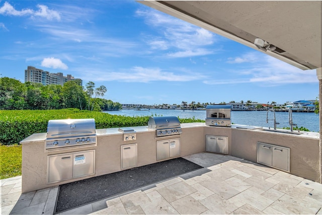 view of patio featuring area for grilling, a water view, and exterior kitchen