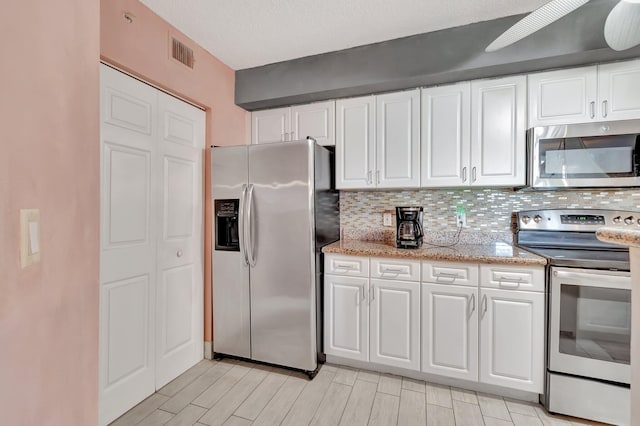 kitchen with white cabinets, ceiling fan, backsplash, and appliances with stainless steel finishes