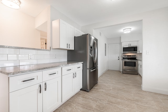 kitchen featuring white cabinets, light stone counters, backsplash, and appliances with stainless steel finishes