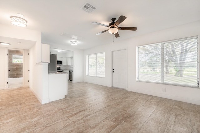 kitchen with white cabinets, light stone counters, a wealth of natural light, and ceiling fan