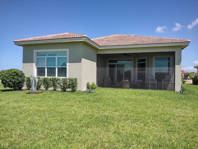 back of property featuring ceiling fan and a yard