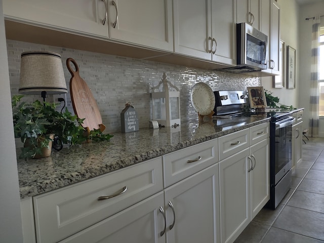 kitchen with white cabinetry, light tile patterned floors, light stone counters, and appliances with stainless steel finishes