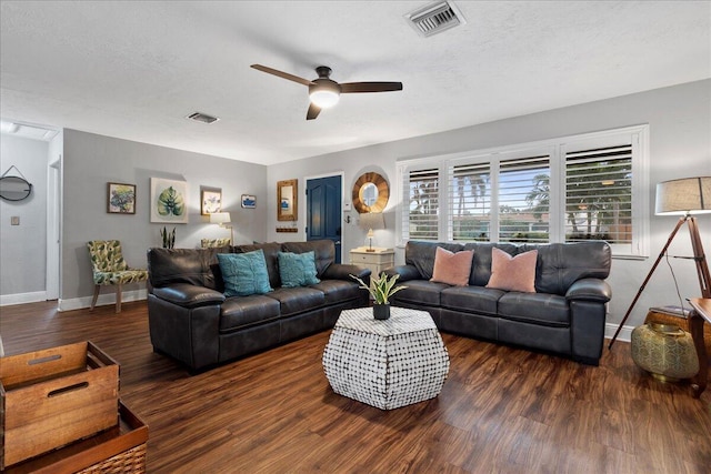 living room featuring ceiling fan, dark wood-type flooring, and a textured ceiling