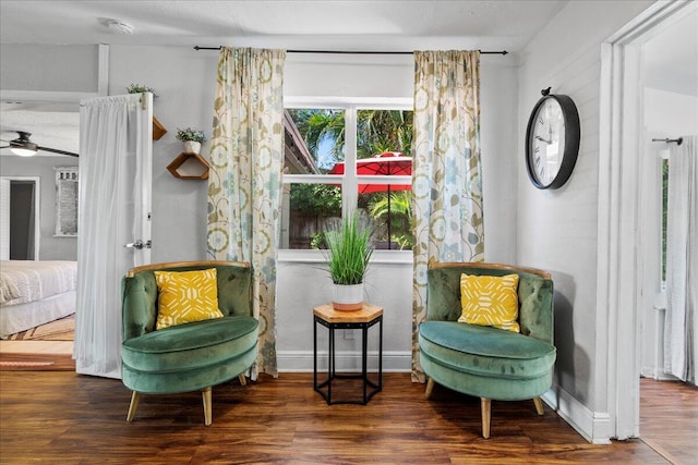 living area featuring ceiling fan and dark wood-type flooring