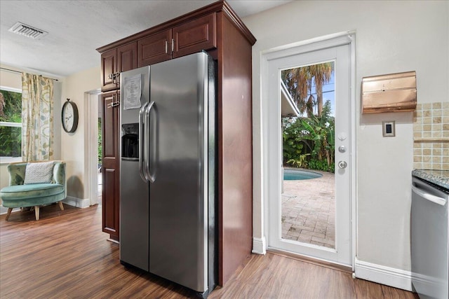 kitchen with a wealth of natural light, dark wood-type flooring, stainless steel appliances, and light stone counters