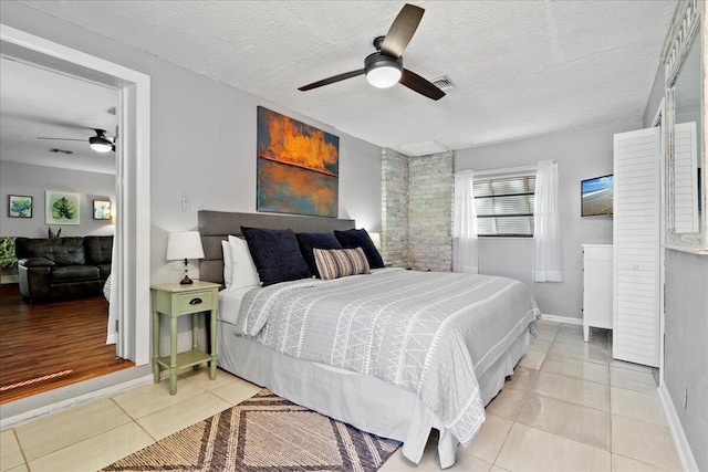 tiled bedroom with ceiling fan and a textured ceiling