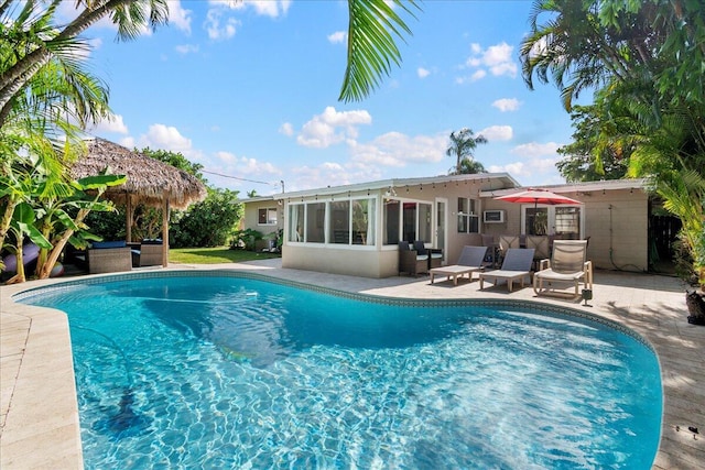 view of swimming pool featuring a patio area and a sunroom