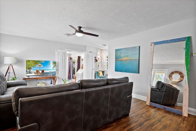 living room with ceiling fan, dark wood-type flooring, and a textured ceiling