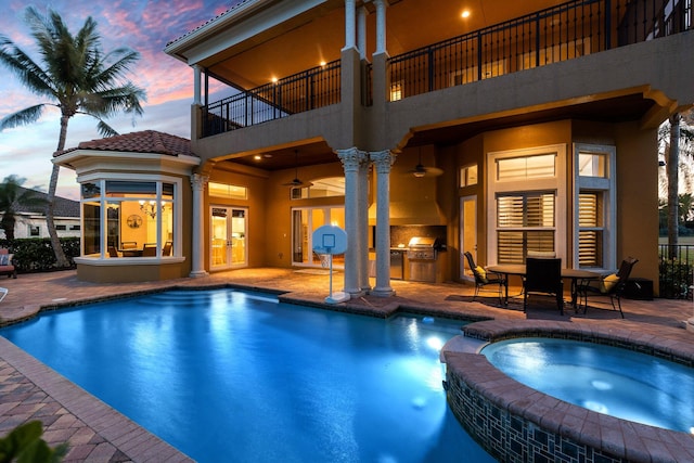 pool at dusk with french doors, an outdoor kitchen, a patio area, an in ground hot tub, and area for grilling