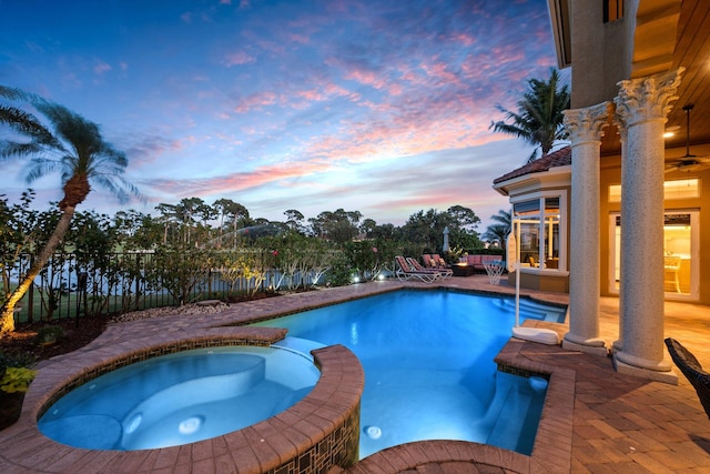 pool at dusk with an in ground hot tub and a patio area