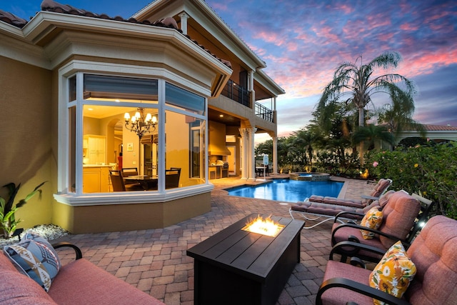 pool at dusk with an in ground hot tub, a patio, and an outdoor fire pit