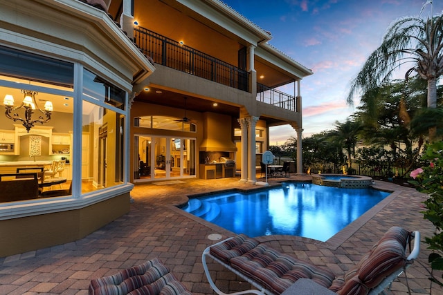 pool at dusk with an in ground hot tub, french doors, a patio, and exterior kitchen