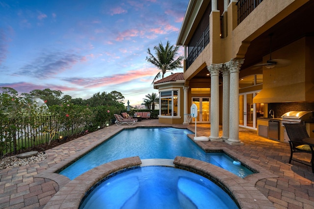 pool at dusk featuring french doors, an in ground hot tub, a grill, exterior kitchen, and a patio